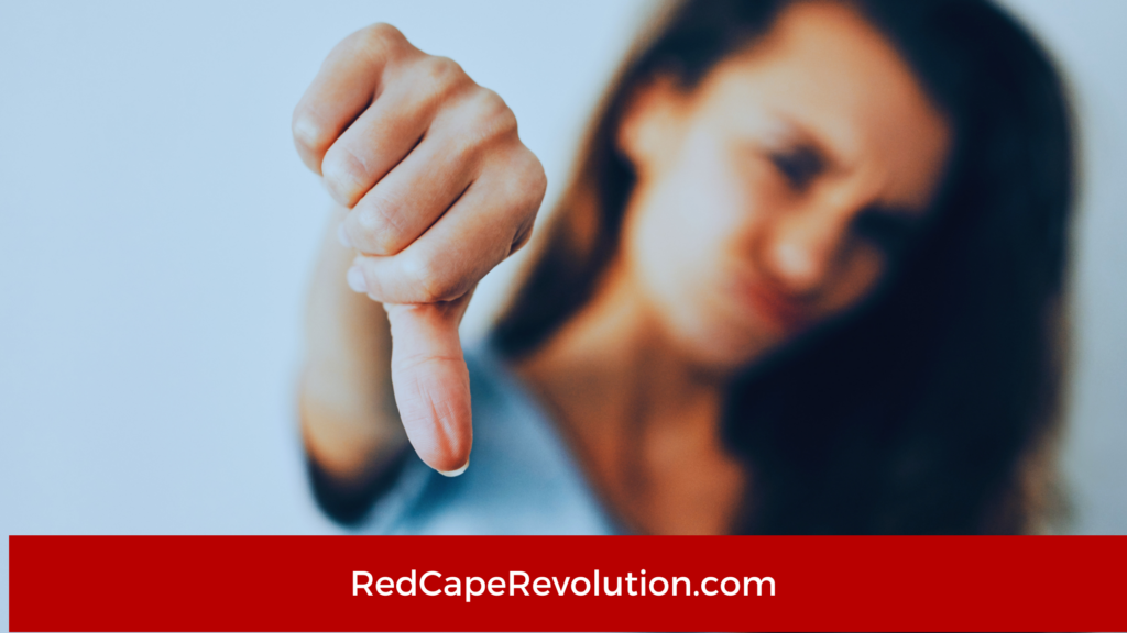 Close-up of a person pointing a finger downward, with a red banner showing 'RedCapeRevolution.com' across the bottom of the image.